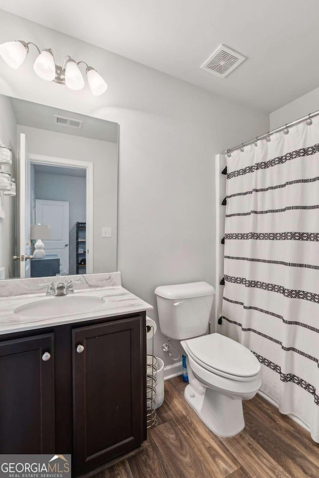 bathroom featuring wood finished floors, vanity, toilet, and curtained shower