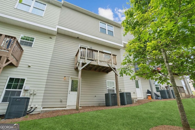 back of house with a balcony, central AC unit, and a lawn