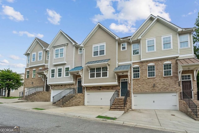 townhome / multi-family property featuring brick siding, a garage, driveway, and a standing seam roof