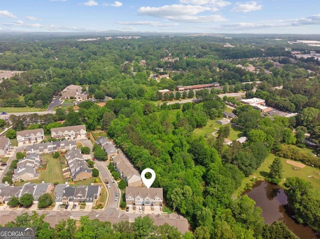 aerial view of residential area featuring a heavily wooded area and a large body of water