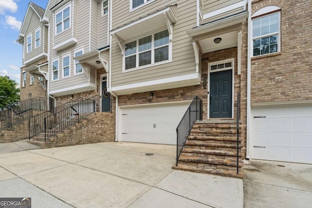 doorway to property featuring an attached garage, driveway, and brick siding