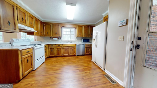 304 5th Ave, Twin City, GA 30471 - kitchen featuring stainless steel appliances, a sink, under cabinet range hood, ornamental molding, and light wood-style flooring