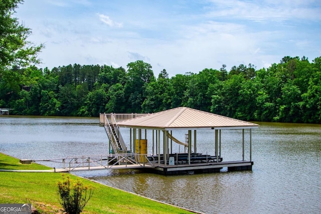 dock with boat lift, a view of trees, and a water view