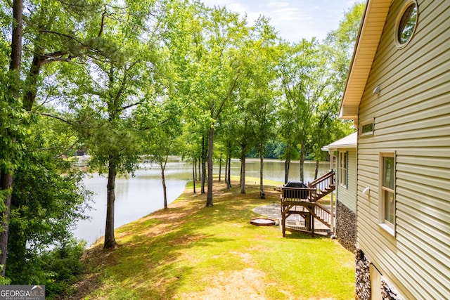 view of green lawn featuring a water view and view of scattered trees