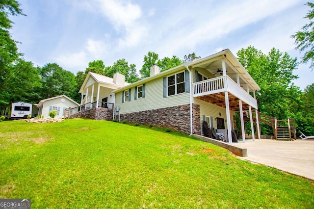 back of property with a ceiling fan, a chimney, a yard, and stairs