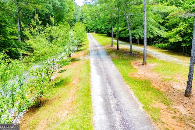 view of asphalt street featuring a wooded view