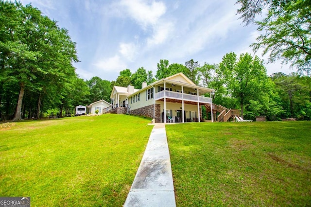 rear view of property with stairway, ceiling fan, and a lawn