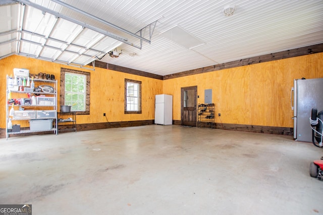 garage with freestanding refrigerator, a garage door opener, and wooden walls