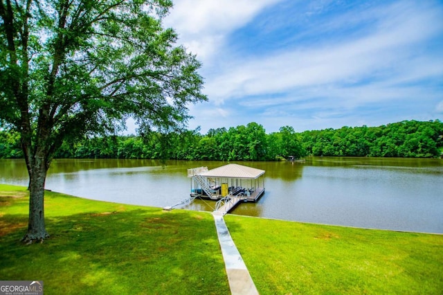 dock with a water view, a lawn, and a wooded view