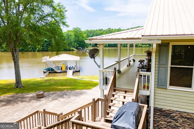 wooden deck with a water view, a boat dock, a yard, and boat lift