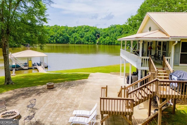 dock featuring stairway, a water view, a patio area, and a lawn