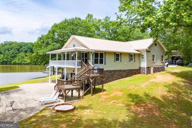 rear view of property with a water view, a lawn, and stairs