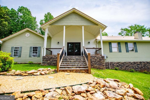 view of front of home featuring french doors, stairs, a chimney, and a front lawn