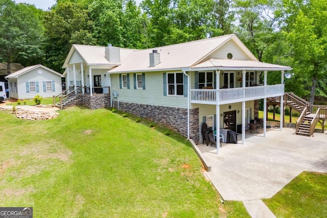 view of front of house with stairs, a chimney, a front yard, metal roof, and a patio area