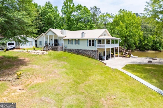 view of front of home with stairs, an outdoor fire pit, a patio, a front yard, and view of wooded area