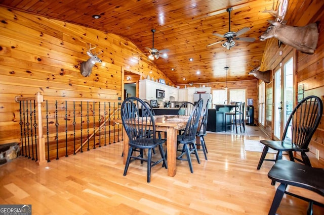 dining area featuring vaulted ceiling, wooden ceiling, light wood-style floors, wood walls, and a ceiling fan