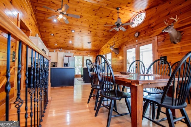 dining area featuring ceiling fan, wooden ceiling, lofted ceiling, light wood-style floors, and wooden walls