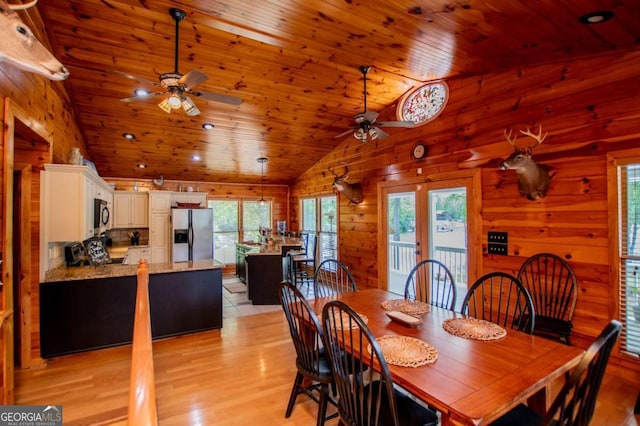 dining area featuring ceiling fan, wood ceiling, vaulted ceiling, light wood-style flooring, and wooden walls