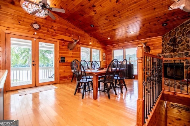dining space with vaulted ceiling, light wood-style flooring, ceiling fan, wood walls, and wooden ceiling