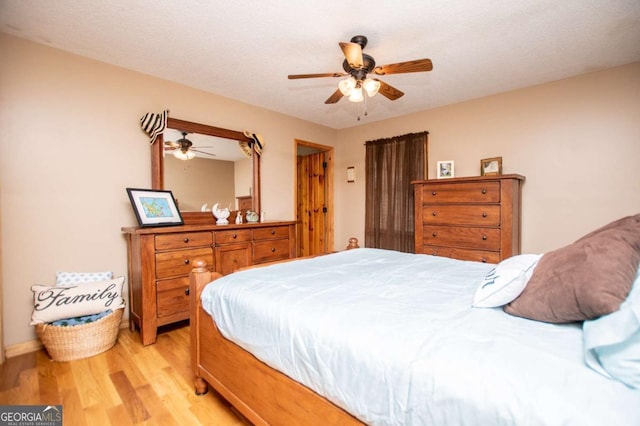 bedroom with light wood-style flooring, a ceiling fan, and baseboards