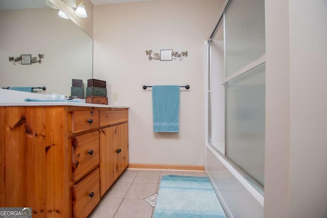 bathroom with tile patterned flooring, vanity, combined bath / shower with glass door, and baseboards