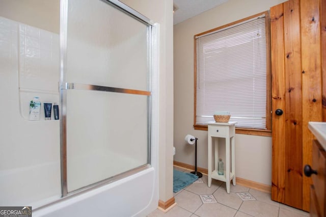 bathroom featuring baseboards, tile patterned floors, toilet, and shower / bath combination with glass door