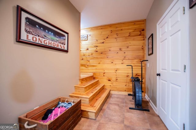 stairway featuring wooden walls, tile patterned flooring, and baseboards