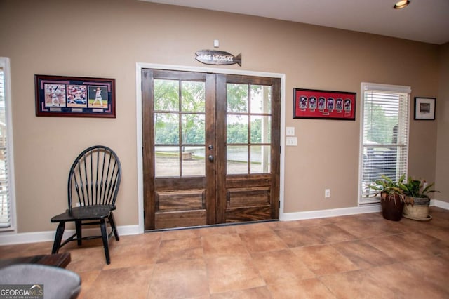 foyer with healthy amount of natural light, french doors, baseboards, and tile patterned floors
