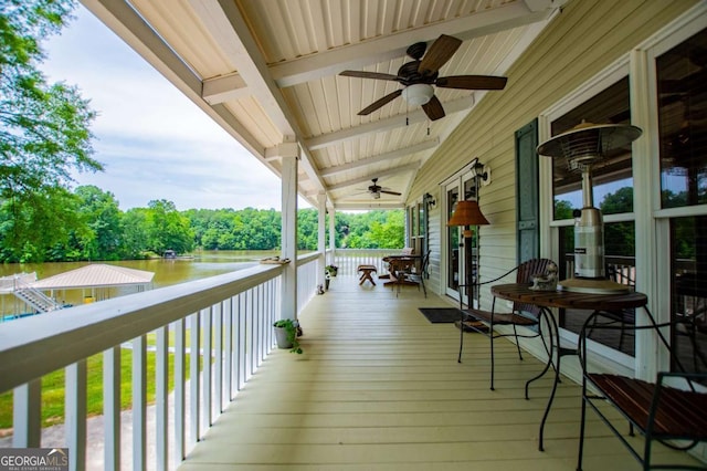 porch with ceiling fan and a water view