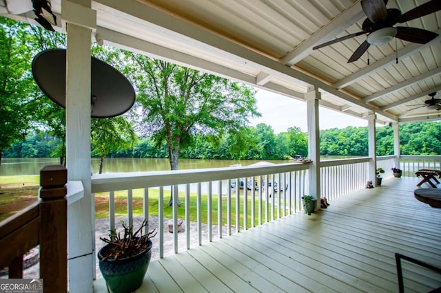 wooden terrace featuring a ceiling fan, a water view, a lawn, and view of wooded area