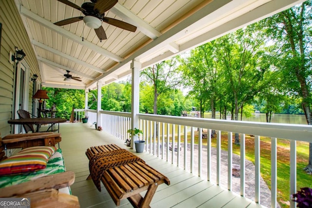 wooden porch with a ceiling fan and view of scattered trees