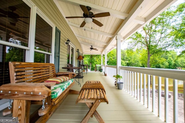 wooden porch with ceiling fan and view of scattered trees