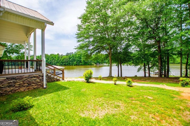 view of grassy yard featuring a water view and covered porch