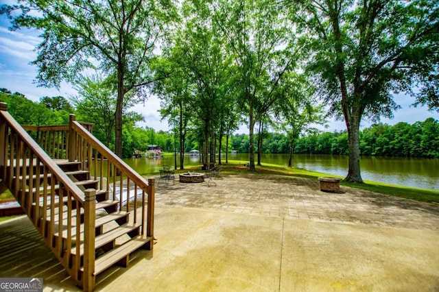 view of patio / terrace featuring an outdoor fire pit, stairway, and a water view