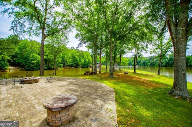 view of patio / terrace featuring an outdoor fire pit, a water view, and view of scattered trees
