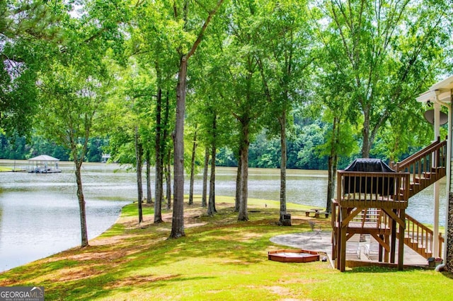 view of green lawn featuring a water view and stairs