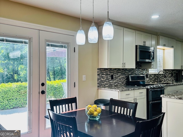 6940 Treeline Dr, Cumming, GA 30028 - kitchen featuring stainless steel microwave, range with two ovens, backsplash, a sink, and white cabinetry