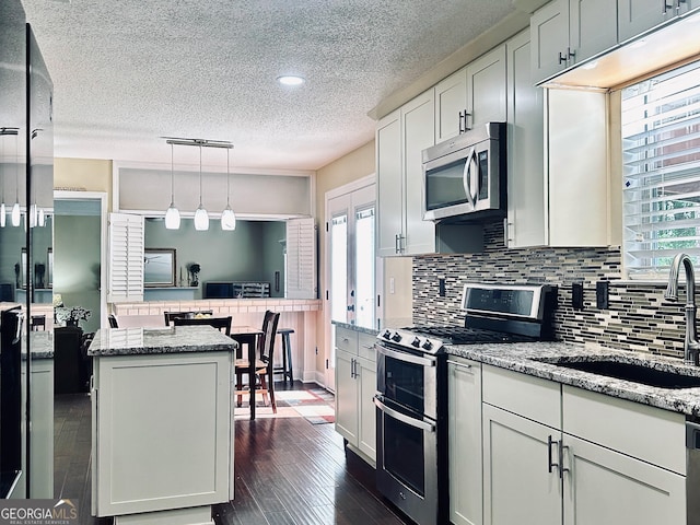 6940 Treeline Dr, Cumming, GA 30028 - kitchen with stainless steel appliances, a sink, a textured ceiling, decorative backsplash, and dark wood-style floors