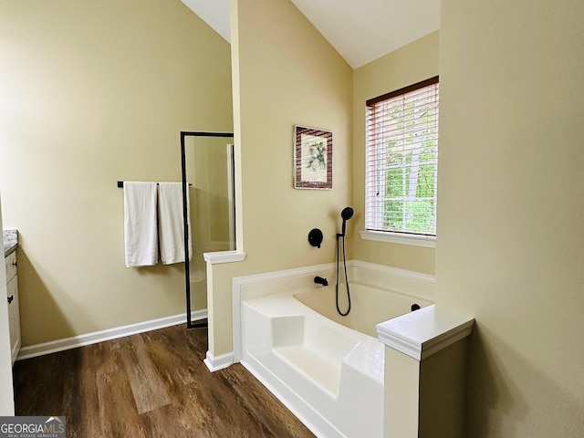 6940 Treeline Dr, Cumming, GA 30028 - bathroom with wood finished floors, a bath, vaulted ceiling, and baseboards