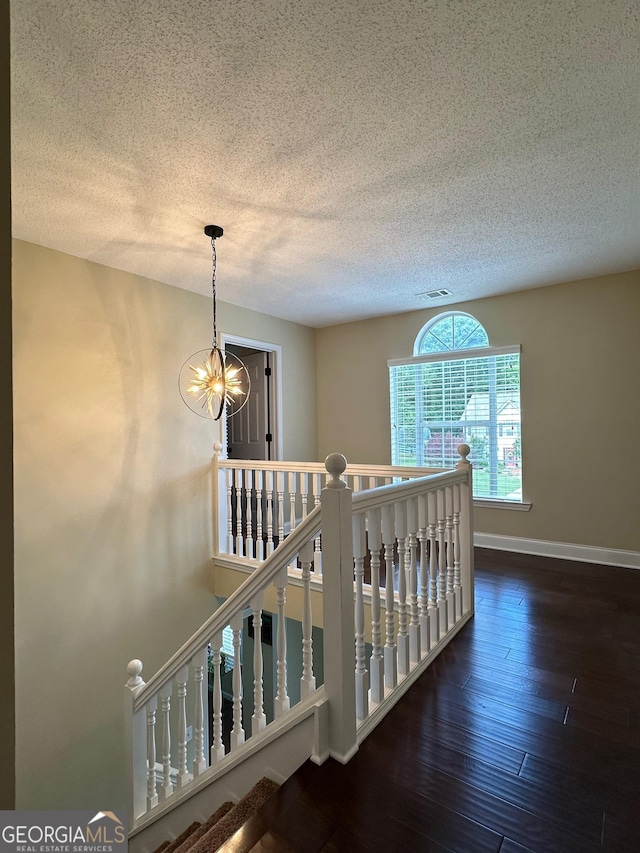 6940 Treeline Dr, Cumming, GA 30028 - hallway featuring a chandelier, a textured ceiling, hardwood / wood-style floors, an upstairs landing, and baseboards