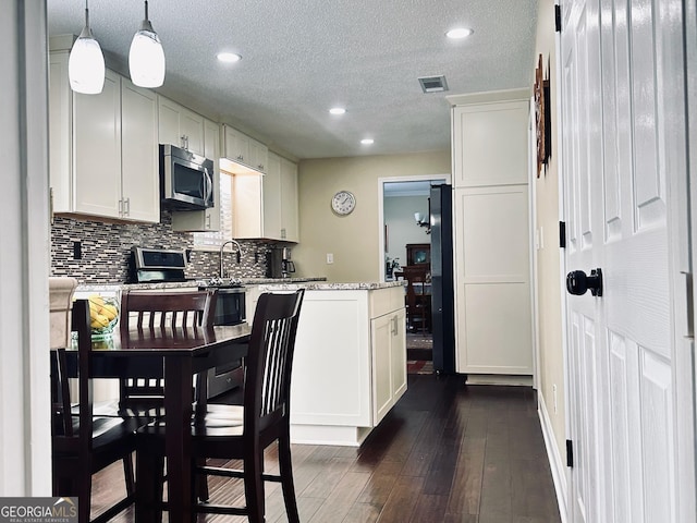 6940 Treeline Dr, Cumming, GA 30028 - kitchen with stainless steel microwave, a peninsula, tasteful backsplash, recessed lighting, and dark wood-type flooring