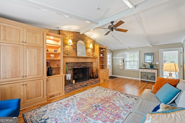 living area featuring light wood-style flooring, ceiling fan, a brick fireplace, and baseboards