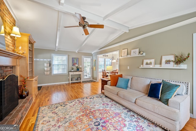 living room with wood finished floors, a brick fireplace, ceiling fan, and a chandelier
