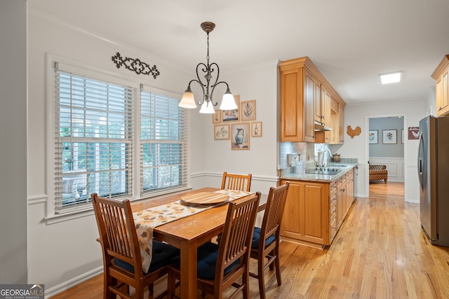 dining room with a chandelier, ornamental molding, and light wood-style flooring