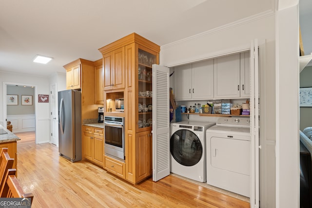 kitchen featuring appliances with stainless steel finishes, independent washer and dryer, crown molding, light wood-style flooring, and glass insert cabinets