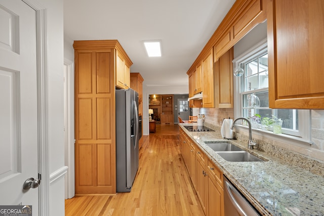 kitchen featuring a sink, stainless steel refrigerator with ice dispenser, light wood-style flooring, black electric cooktop, and light stone counters