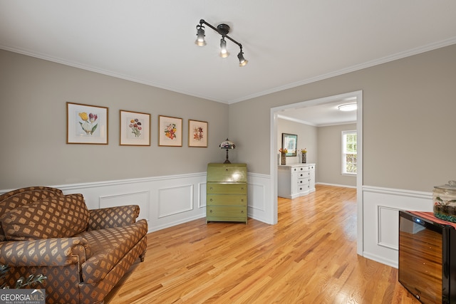 sitting room featuring wine cooler, light wood finished floors, crown molding, and wainscoting