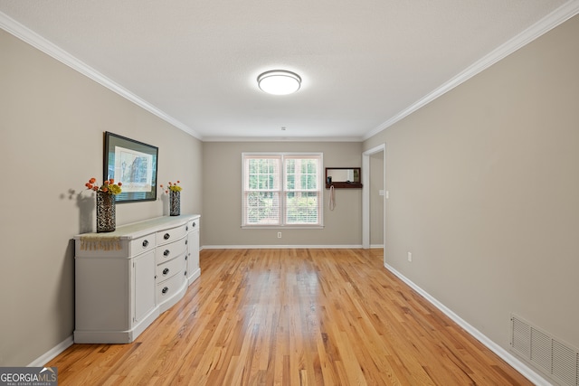 spare room featuring light wood-style floors, ornamental molding, and baseboards