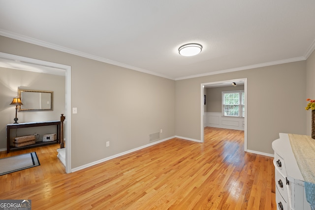 unfurnished room featuring light wood finished floors, crown molding, and baseboards