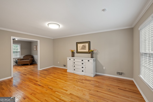 unfurnished bedroom featuring light wood-style floors, crown molding, and baseboards